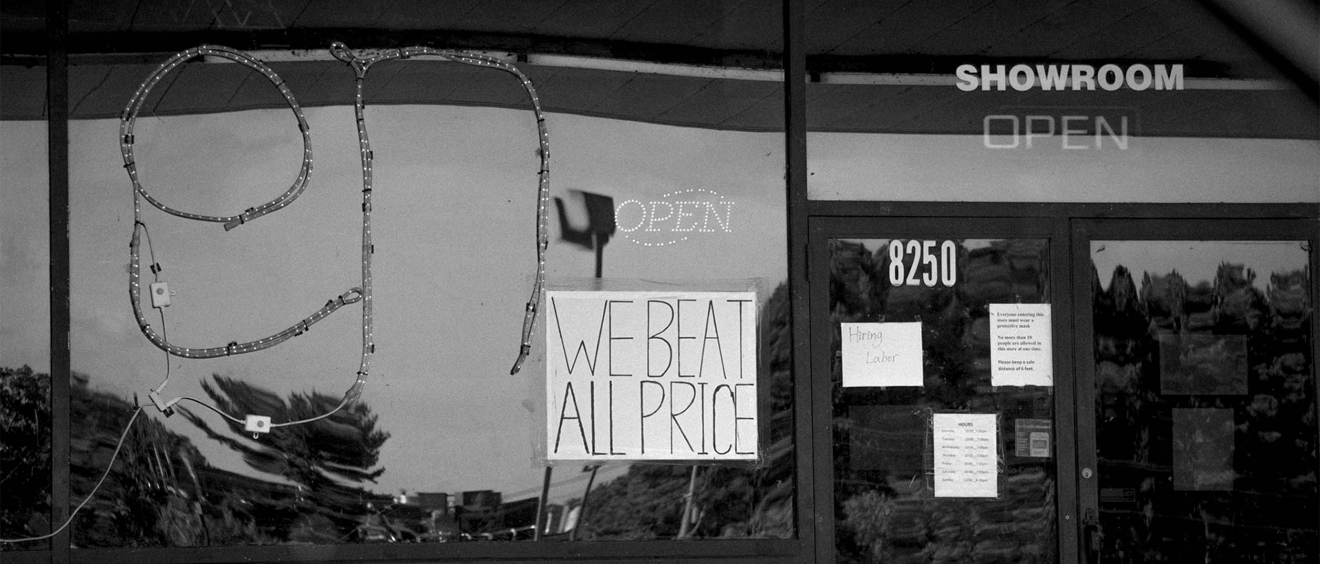 Signs on the Diamond Point Home Furnishings building reading We beat all price, hiring labor, and open